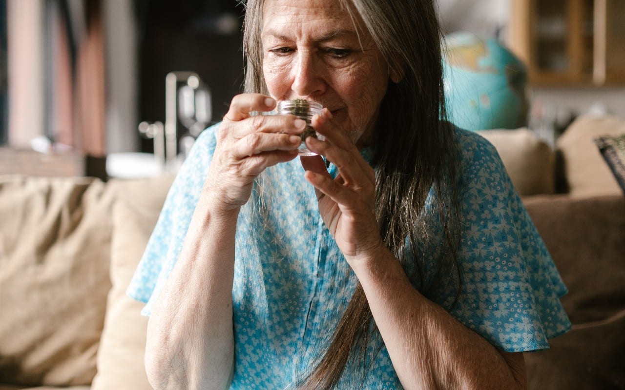 old woman smelling her marijuana to check for mold
